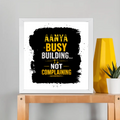 Framed Poster | Multiple Sizes & Frame Colors | 300 GSM Art Paper, Laminated | Fade-Proof Digital Print, Mounting Kit Included | Unisex | Personalized | Typographic | Work Ethic | Success | Everyday | Motivational | Busy Building, Not Complaining - front_12x12In - 12x12In - mockup 5